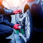 Car mechanic installing sensor during suspension adjustment. Wheel alignment work at repair service station