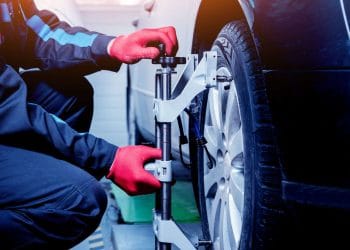 Car mechanic installing sensor during suspension adjustment. Wheel alignment work at repair service station