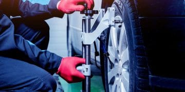 Car mechanic installing sensor during suspension adjustment. Wheel alignment work at repair service station