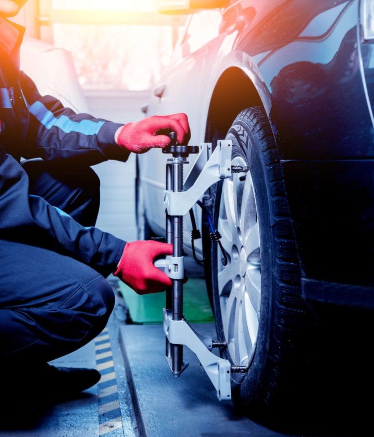 Car mechanic installing sensor during suspension adjustment. Wheel alignment work at repair service station