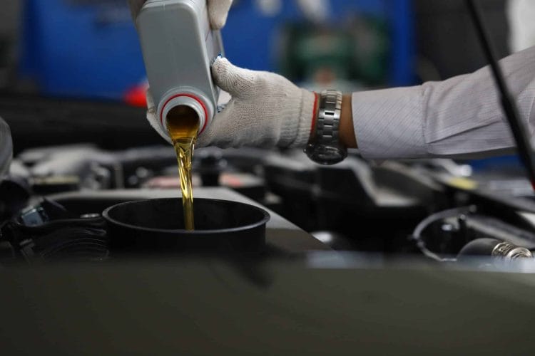 Close-up of mechanic replacing and pouring motor oil to car engine. Automobile maintenance and repair service station concept. Professional garage workers