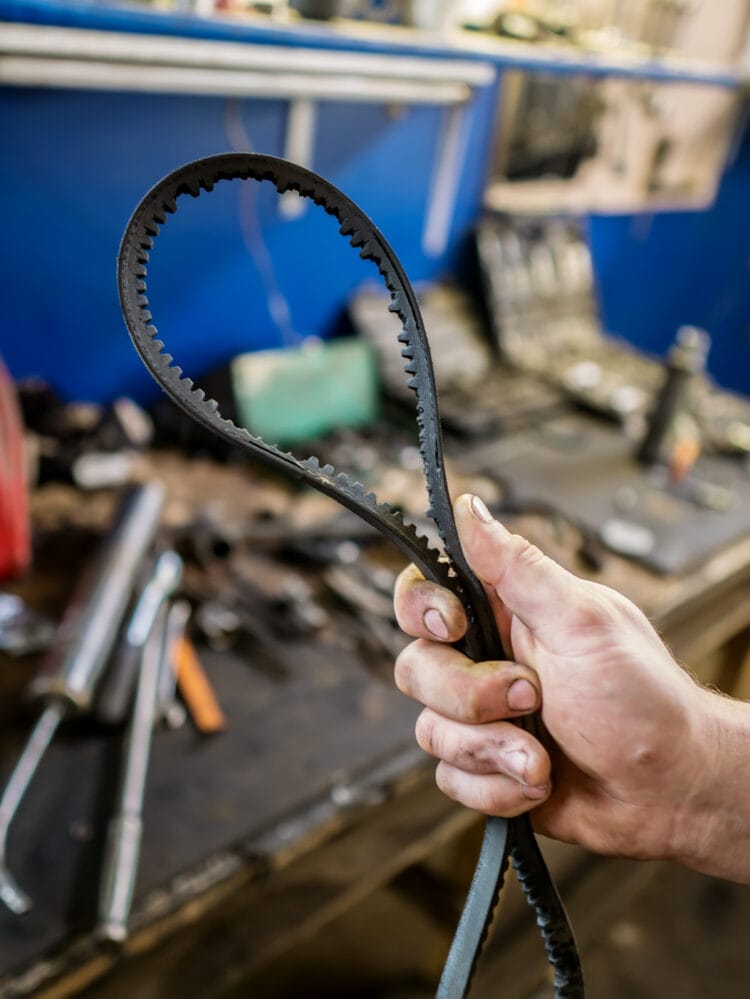 Old worn rubber alternator belt in men's hands. The concept of car maintenance. Copy space