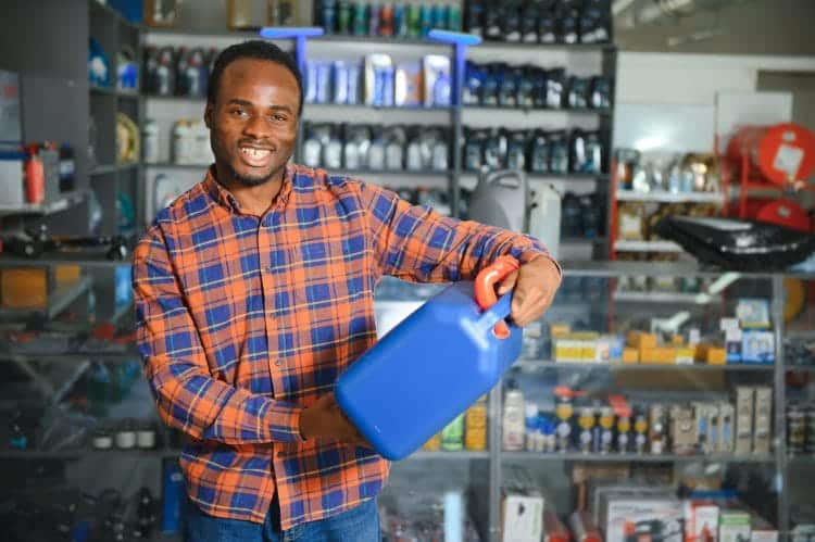 seller man with canister of motor oil in auto store.