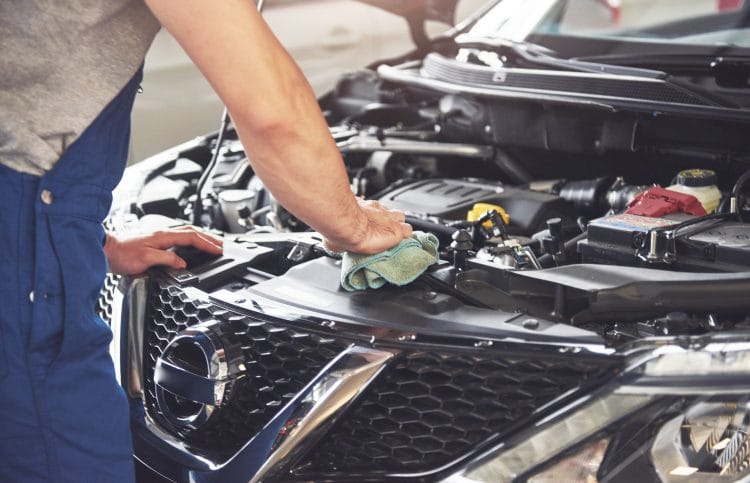 Picture showing muscular car service worker repairing vehicle.