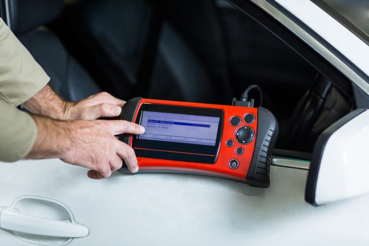 Hands of mechanic using a diagnostic tool in repair garage