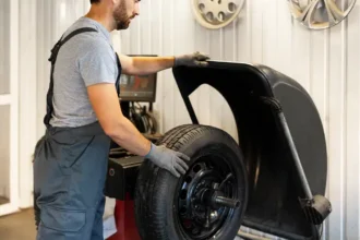 Mecânico realizando o balanceamento de rodas em uma máquina de oficina, ajustando o peso do pneu para garantir estabilidade e reduzir vibrações no veículo.