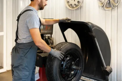 Mec&acirc;nico realizando o balanceamento de rodas em uma m&aacute;quina de oficina, ajustando o peso do pneu para garantir estabilidade e reduzir vibra&ccedil;&otilde;es no ve&iacute;culo.