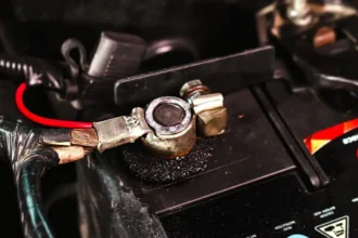 Close-up de terminal de bateria automotiva com sinais de oxidação e corrosão, destacando a importância da manutenção preventiva e da limpeza correta dos cabos para garantir bom funcionamento elétrico do veículo.