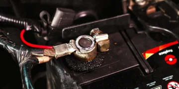 Close-up de terminal de bateria automotiva com sinais de oxidação e corrosão, destacando a importância da manutenção preventiva e da limpeza correta dos cabos para garantir bom funcionamento elétrico do veículo.