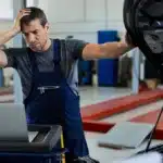 Mecânico preocupado analisando o motor de um carro após uma troca de óleo, representando falhas no veículo causadas por manutenção incorreta ou problemas no lubrificante.