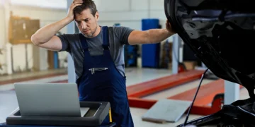 Mecânico preocupado analisando o motor de um carro após uma troca de óleo, representando falhas no veículo causadas por manutenção incorreta ou problemas no lubrificante.