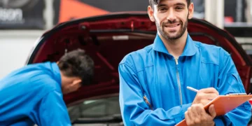Mecânico sorridente em oficina realizando checklist de revisão de veículo antes de uma viagem, simbolizando a importância da manutenção preventiva e da preparação do carro para trajetos longos com segurança e tranquilidade.