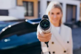 Mulher segurando um plugue de carregamento de carro elétrico em destaque, simbolizando a transição tecnológica dos veículos flex-híbridos que combinam etanol, gasolina e energia elétrica.