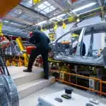 Linha de montagem de veículos em fábrica brasileira, mostrando trabalhadores atuando na produção de carros sustentáveis, ilustrando o impacto do programa Mover e da isenção do IPI zero.