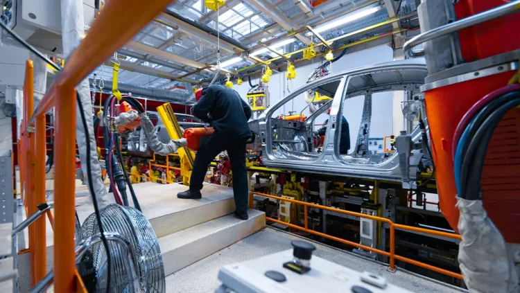 Linha de montagem de veículos em fábrica brasileira, mostrando trabalhadores atuando na produção de carros sustentáveis, ilustrando o impacto do programa Mover e da isenção do IPI zero.