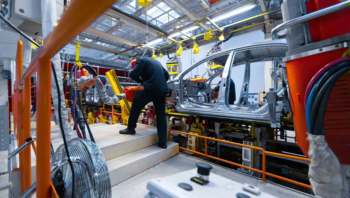 Linha de montagem de veículos em fábrica brasileira, mostrando trabalhadores atuando na produção de carros sustentáveis, ilustrando o impacto do programa Mover e da isenção do IPI zero.