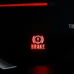 "Luz de freio acesa no painel do carro indicando alerta no sistema de frenagem"