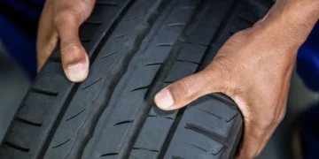 Pessoa verificando o desenho da banda de rodagem de um pneu de inverno, destacando os sulcos profundos e o padrão próprio para maior aderência em pistas molhadas ou frias.