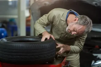 Mecânico inspecionando um pneu remold em oficina automotiva, verificando a qualidade da banda de rodagem e o estado da borracha reformada.