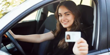 Mulher sorridente dentro de um carro segurando sua CNH, simbolizando a conquista da habilitação gratuita pelo programa CNH Social destinado a pessoas de baixa renda.