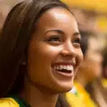 Mulher sorrindo vestida com as cores do Brasil em meio à multidão, representando o entusiasmo dos fãs no Grande Prêmio de São Paulo 2025, que bateu recorde histórico de público em Interlagos.