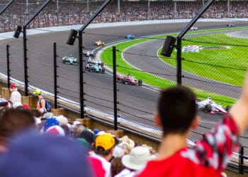 Torcedores vibram nas arquibancadas enquanto carros de Fórmula 1 passam em alta velocidade no circuito, simbolizando o recorde de público e a energia contagiante do Grande Prêmio de São Paulo 2025.