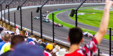 Torcedores vibram nas arquibancadas enquanto carros de Fórmula 1 passam em alta velocidade no circuito, simbolizando o recorde de público e a energia contagiante do Grande Prêmio de São Paulo 2025.