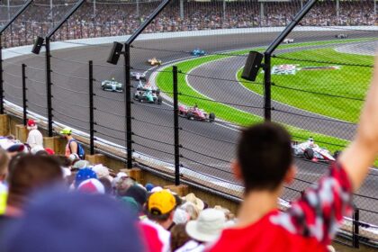 Torcedores vibram nas arquibancadas enquanto carros de F&oacute;rmula 1 passam em alta velocidade no circuito, simbolizando o recorde de p&uacute;blico e a energia contagiante do Grande Pr&ecirc;mio de S&atilde;o Paulo 2025.