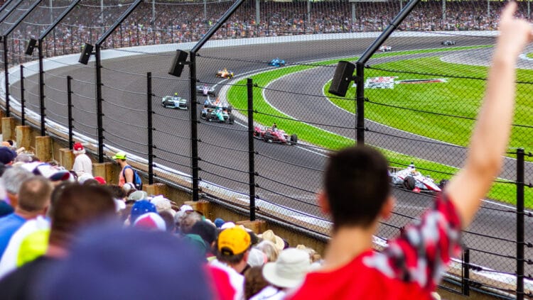 Torcedores vibram nas arquibancadas enquanto carros de Fórmula 1 passam em alta velocidade no circuito, simbolizando o recorde de público e a energia contagiante do Grande Prêmio de São Paulo 2025.