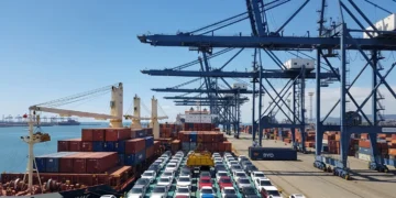 Cena de porto de Santos com navios carregados de carros elétricos da BYD sob céu ensolarado, destacando importação de carros elétricos que
