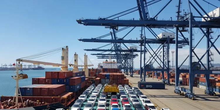 Cena de porto de Santos com navios carregados de carros elétricos da BYD sob céu ensolarado, destacando importação de carros elétricos que