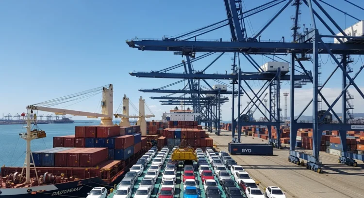 Cena de porto de Santos com navios carregados de carros elétricos da BYD sob céu ensolarado, destacando importação de carros elétricos que