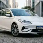 Carro compacto branco com placa Mercosul fictícia GDA2A29, na rua urbana moderna, destacando placa obrigatória em 2026