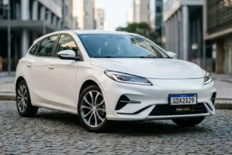 Carro compacto branco com placa Mercosul fictícia GDA2A29, na rua urbana moderna, destacando placa obrigatória em 2026