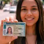 Mulher jovem segura carteira de motorista brasileira borrada, destacando a palavra-chave 'cnh social 2026 descubra' em uma foto realista ao ar livre.