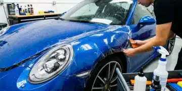 Carro com pintura protegida por proteção cerâmica ou selantes na oficina, técnico ajustando camada de proteção, detalhes de ferramentas, brilho na pintura