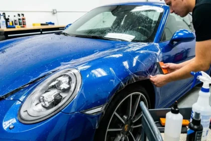 Carro com pintura protegida por prote&ccedil;&atilde;o cer&acirc;mica ou selantes na oficina, t&eacute;cnico ajustando camada de prote&ccedil;&atilde;o, detalhes de ferramentas, brilho na pintura