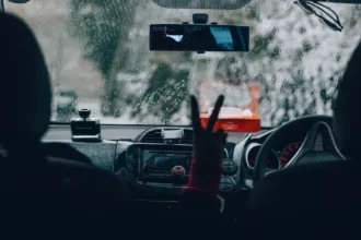 Motorista dirigindo sob forte chuva, com o para-brisa coberto por gotas e baixa visibilidade à frente, simbolizando a importância da manutenção preventiva para evitar aquaplanagem e falhas elétricas durante temporais.