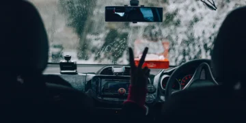 Motorista dirigindo sob forte chuva, com o para-brisa coberto por gotas e baixa visibilidade à frente, simbolizando a importância da manutenção preventiva para evitar aquaplanagem e falhas elétricas durante temporais.