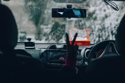 Motorista dirigindo sob forte chuva, com o para-brisa coberto por gotas e baixa visibilidade &agrave; frente, simbolizando a import&acirc;ncia da manuten&ccedil;&atilde;o preventiva para evitar aquaplanagem e falhas el&eacute;tricas durante temporais.