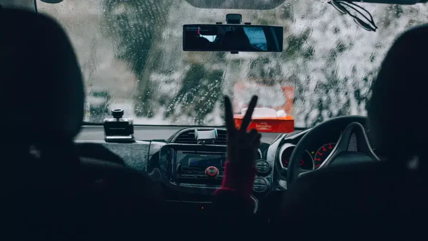 Motorista dirigindo sob forte chuva, com o para-brisa coberto por gotas e baixa visibilidade à frente, simbolizando a importância da manutenção preventiva para evitar aquaplanagem e falhas elétricas durante temporais.