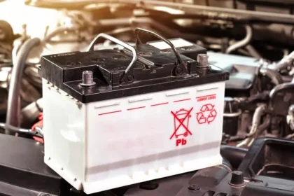 Bateria automotiva sobre o compartimento do motor com s&iacute;mbolo de reciclagem, representando o tema de baterias recondicionadas e novas para ve&iacute;culos.