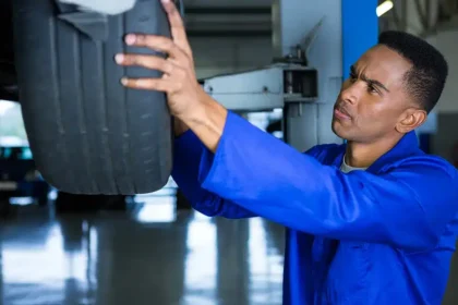 Mec&acirc;nico realizando o rod&iacute;zio de pneus em uma oficina, levantando o ve&iacute;culo com macaco hidr&aacute;ulico e verificando o desgaste dos pneus para garantir uma troca equilibrada.