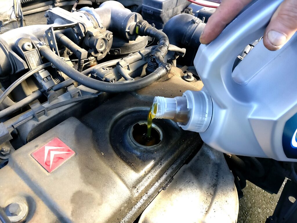 Óleo de motor, o mais importante dos lubrificantes automotivos, sendo colocado pelo bocal de abastecimento. Complete aos poucos e confira a vareta: o nível certo fica entre o MIN e o MAX.