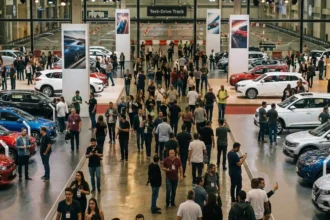 Imagem hiper-realista de salão automóvel movimentado com visitantes, carros variados e ambientes de feira.