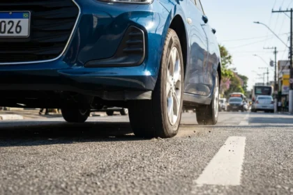 Imagem hiper-realista de pneu com press&atilde;o baixa em carro urbano brasileiro, destacando erro pneus pode aumentar impacto no consumo