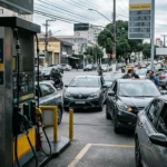 Imagem de um posto de gasolina brasileiro parcialmente vazio, com motoristas preocupados, refletindo a crise do preço gasolina pode bater R$ 10.