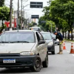 Multas Graves 2026: Cena de blitz com policiais federais e carro com pneus carecas e vidros danificados, destaque para multas graves 2026