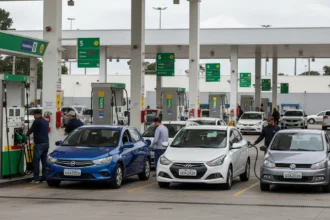 Cena de posto de combustível brasileiro com motoristas abastecendo, destaque para bombas de etanol e gasolina, refletindo o aumento de preço etanol sobe 23 estados