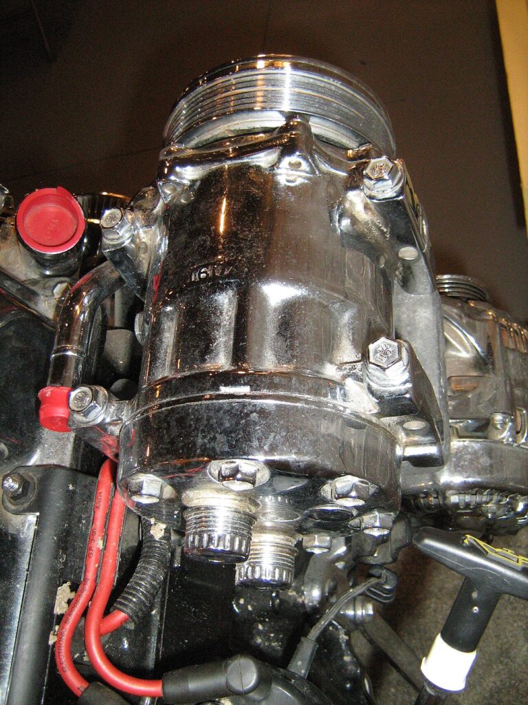 Compressor do ar-condicionado preso ao motor: a polia de cima recebe a correia e gira o compressor.